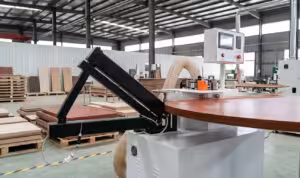 Industrial D5 rocker type edge banding trimming machine performing high-precision trimming on a curved wooden table top in a furniture workshop.